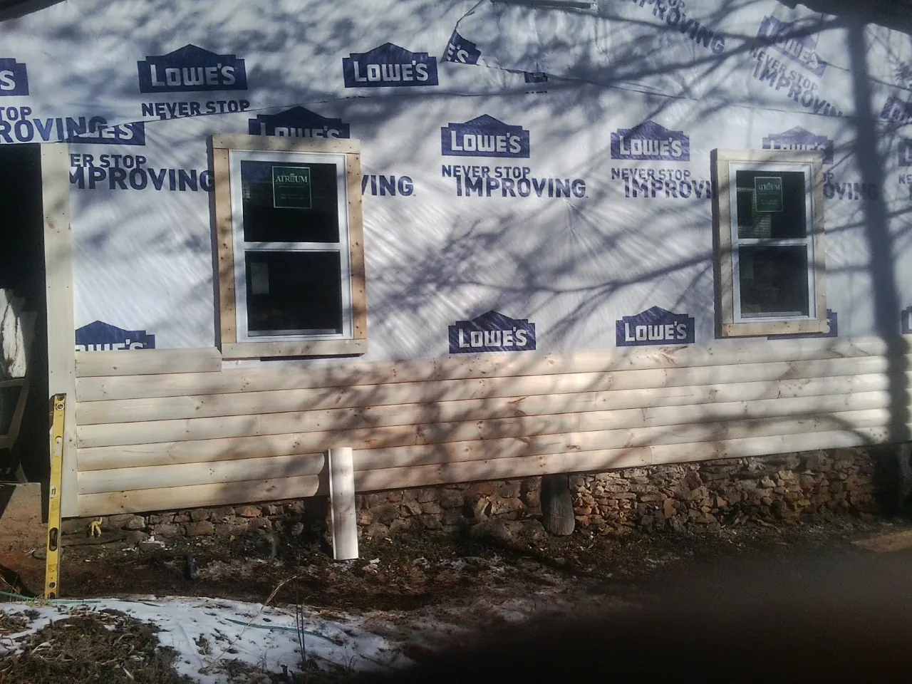 House wrap and new log siding going up on an exterior wall in Lilesville