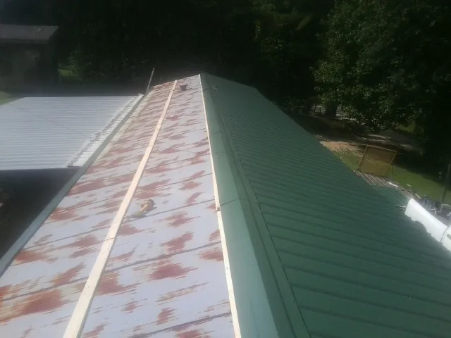Old rusted panels beside newly installed green metal roofing — Wind Damage Roof Repair by Roofing Brothers in Lilesville