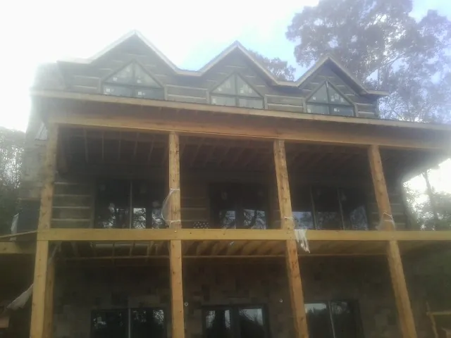 Dormers and porch framing on a large log home under construction — Roof Coating work by our crew in Lilesville