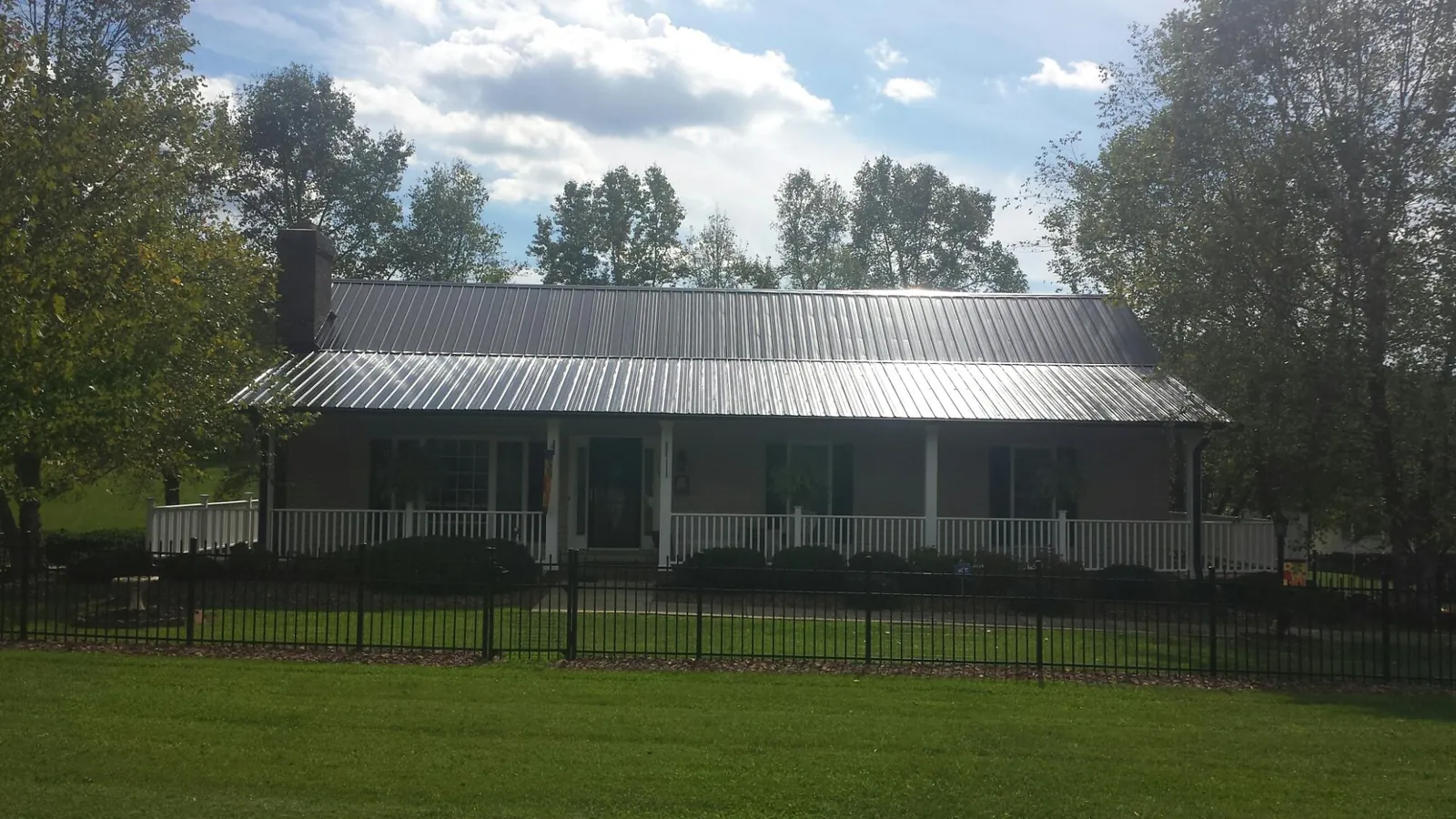 Gray metal roof on a brick ranch with a full width front porch — Gutter Guard Installation work by our crew in Lilesville
