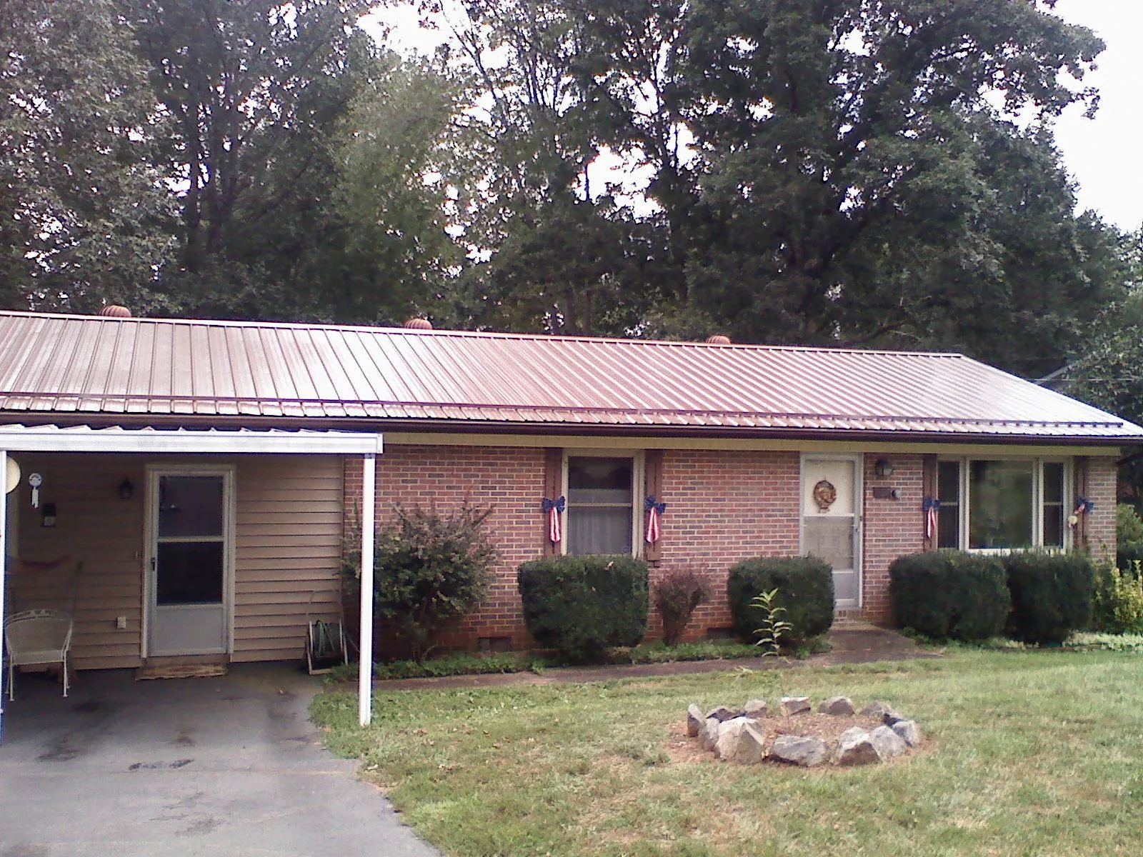 Bronze metal roof and carport on a brick ranch home — Roof Repair work by our crew in Lilesville