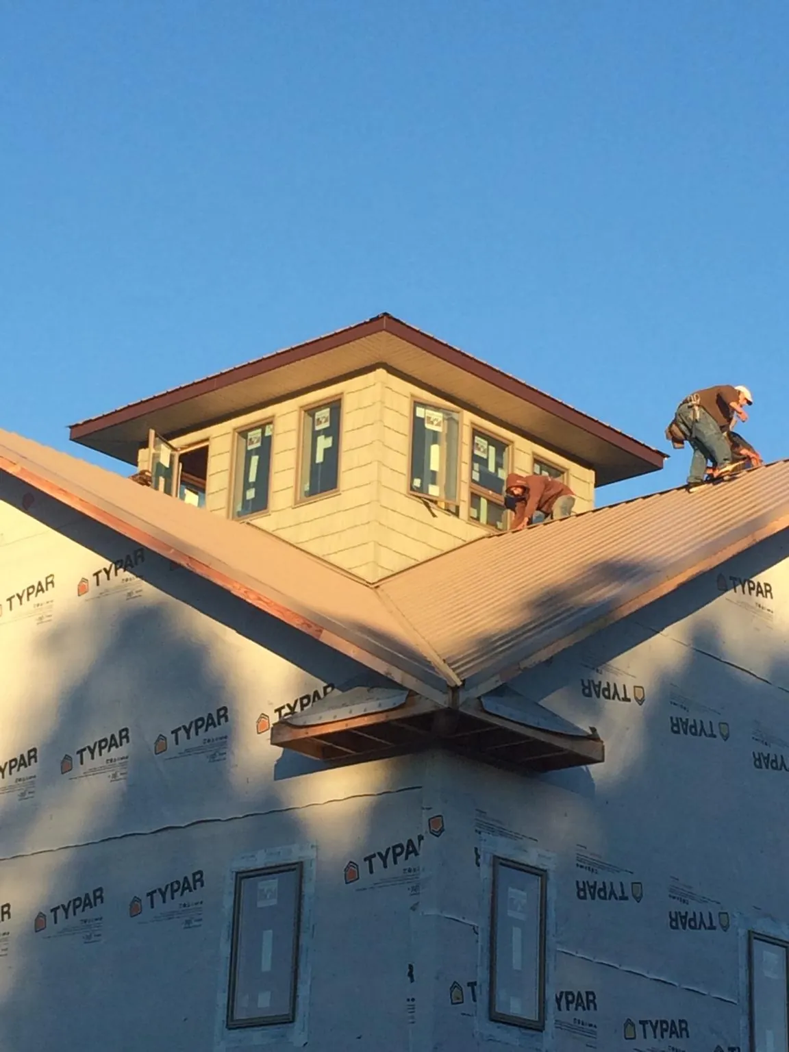 Roofers working around a rooftop cupola on a new metal roof at sunset — Roof Waterproofing in Lilesville by Roofing Brothers